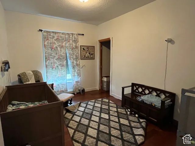 Wood-finish flooring with white baseboards, a window with curtain rod and drapes, and an overhead light fixture