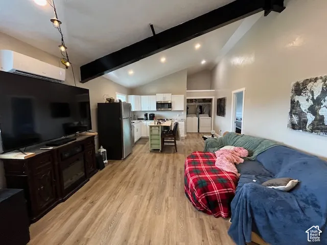 Vaulted ceiling with exposed beam, wood-finish flooring, recessed lighting, and kitchen with white cabinetry