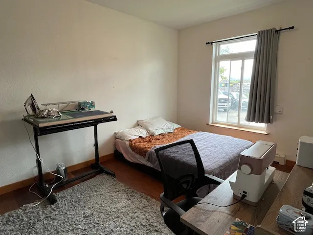 Wood-finish flooring with a single window featuring a curtain rod