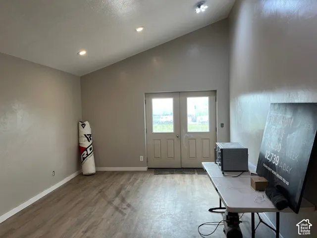 Vaulted ceilings with recessed lighting, wood-finish flooring, and double glass-panel doors