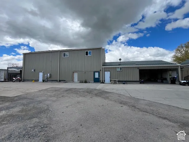 Industrial building with corrugated metal siding, multiple entry doors, and a covered parking area