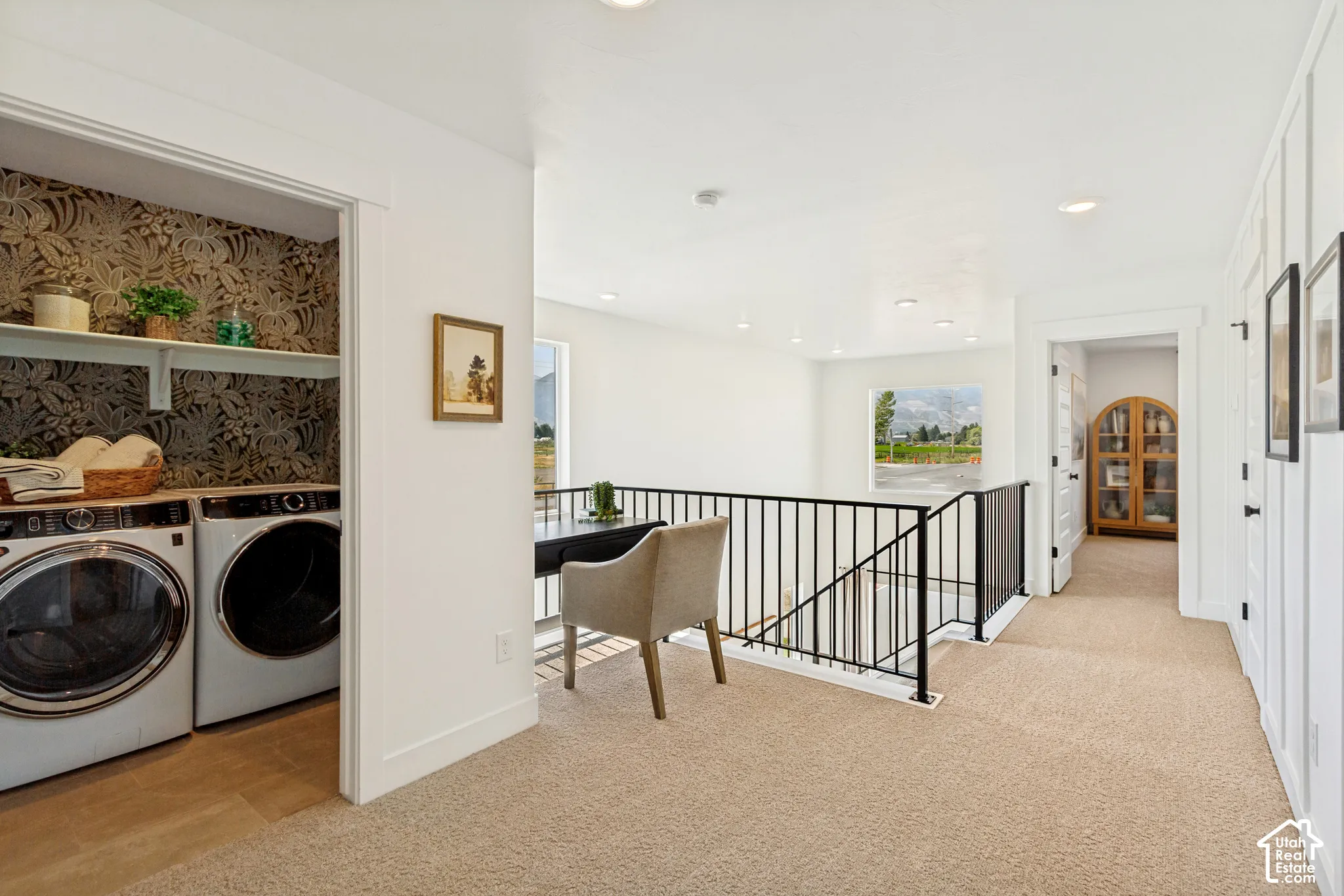 Upper-level laundry closet with patterned wallpaper, built-in shelving, and wood-finish flooring