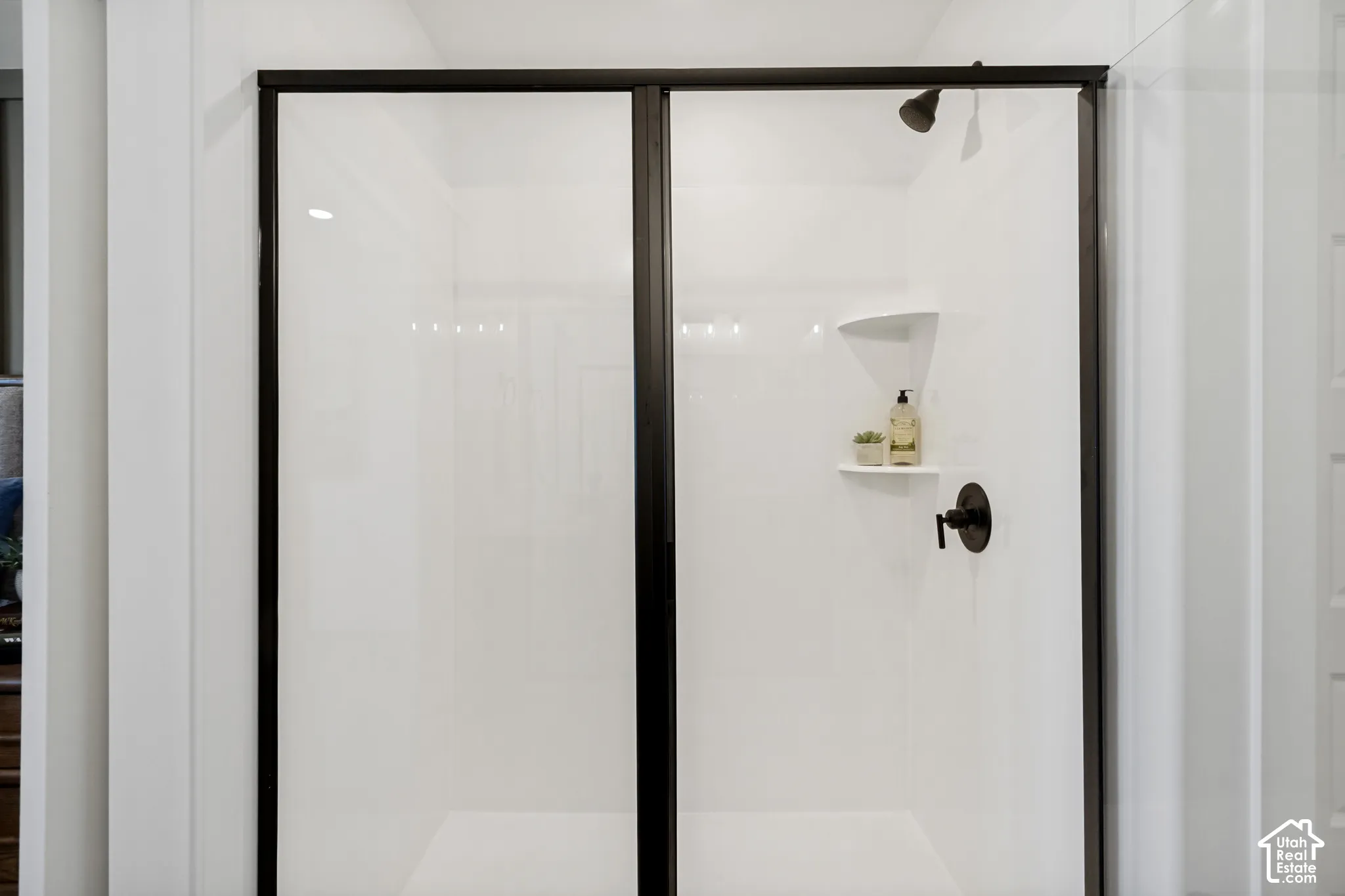 White shower enclosure with a dark-framed sliding glass door