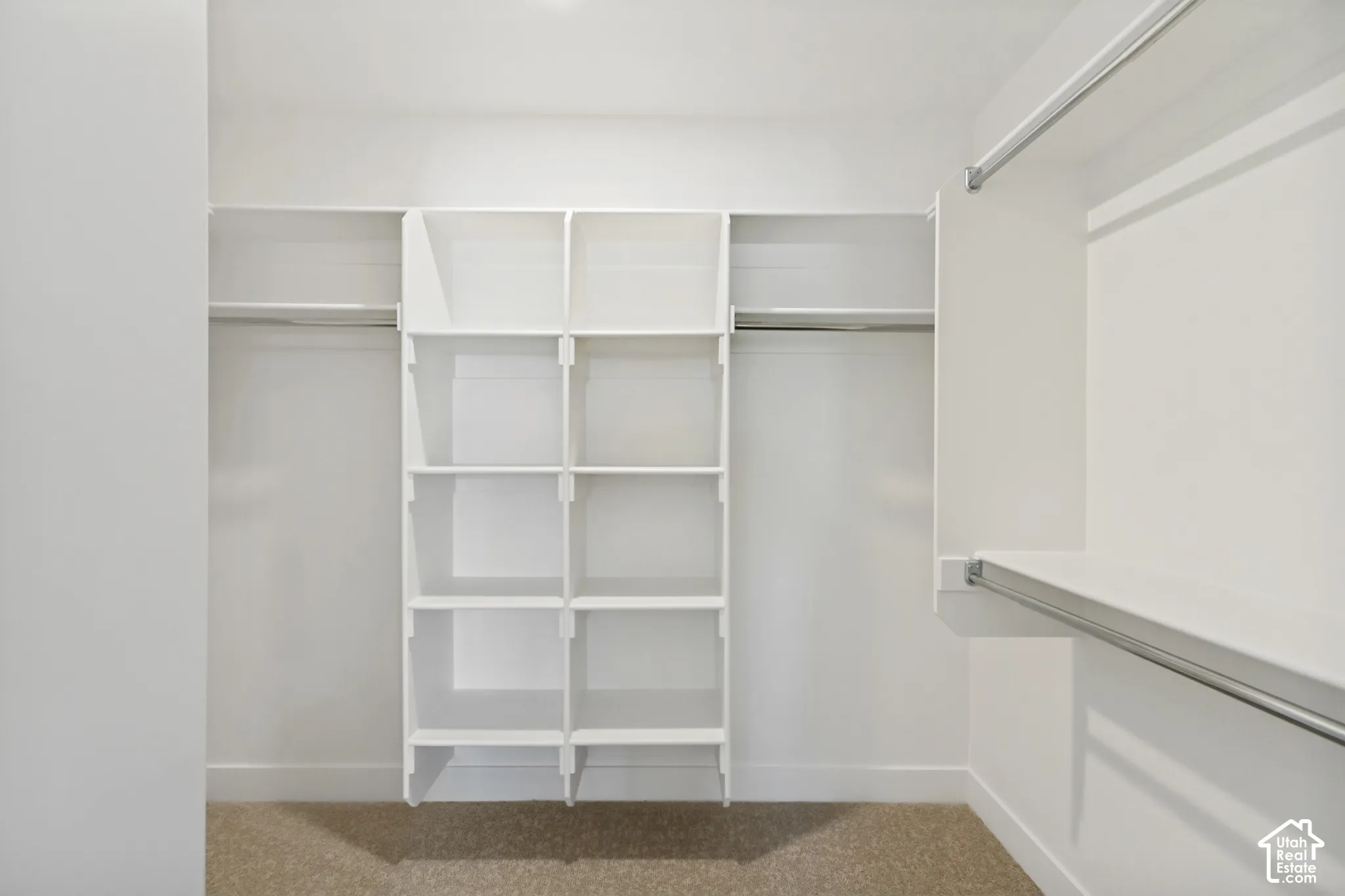 Integrated closet organization system featuring white shelving units and metal hanging rods