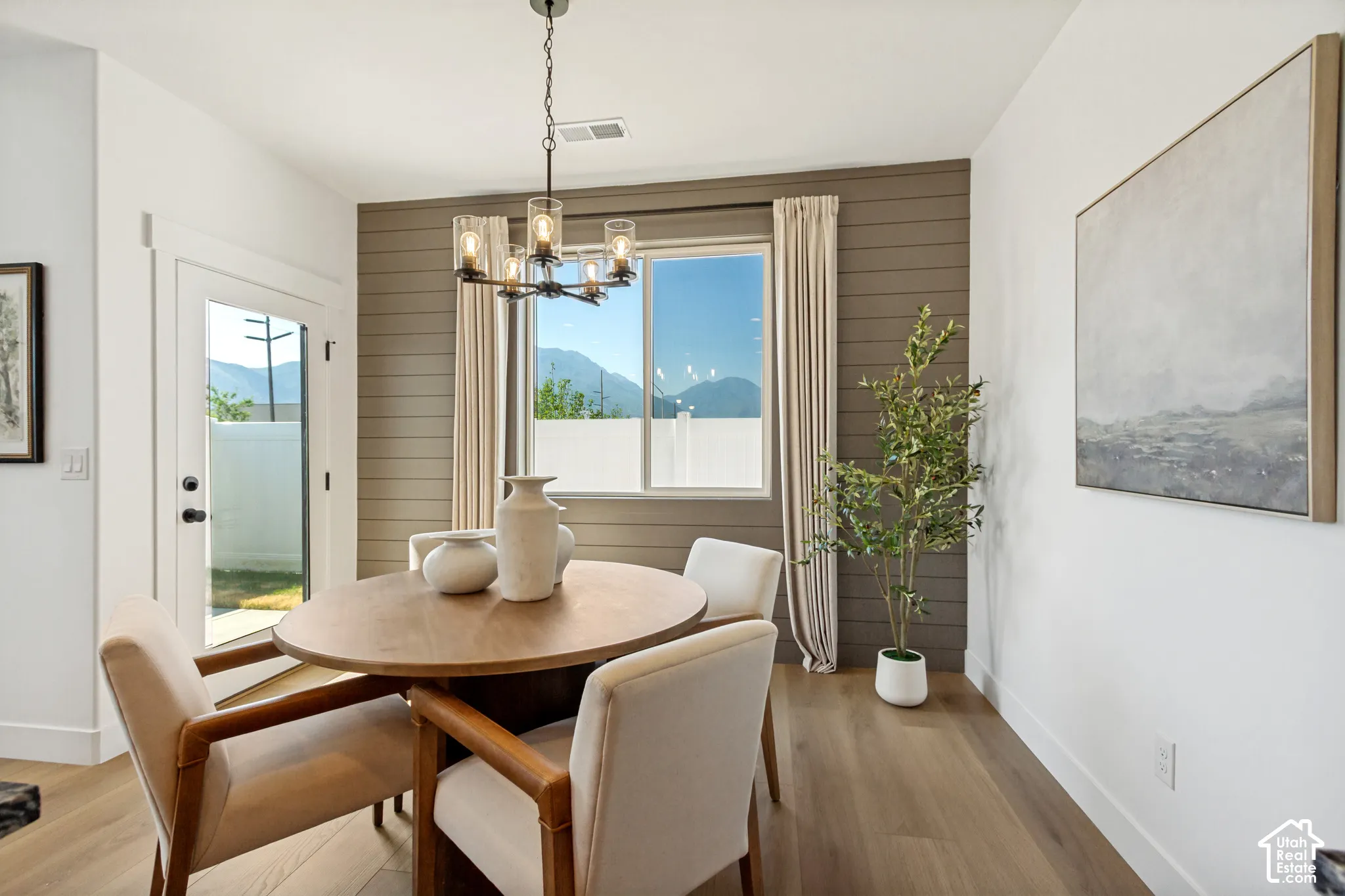 Wood-finish flooring, accent wall with horizontal paneling, and a contemporary chandelier