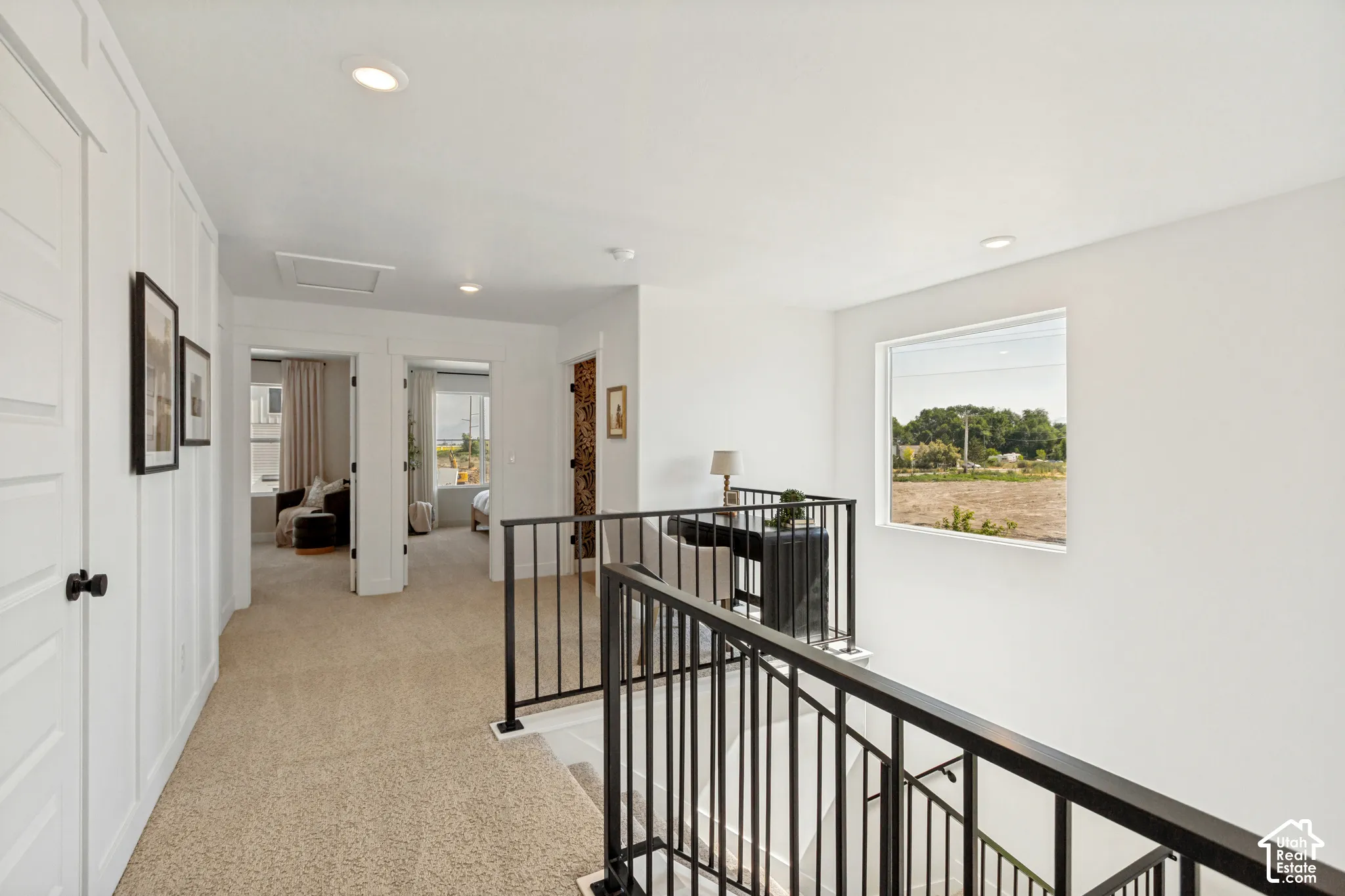 Upper-level hallway with neutral carpeting, recessed lighting, and white paneled walls