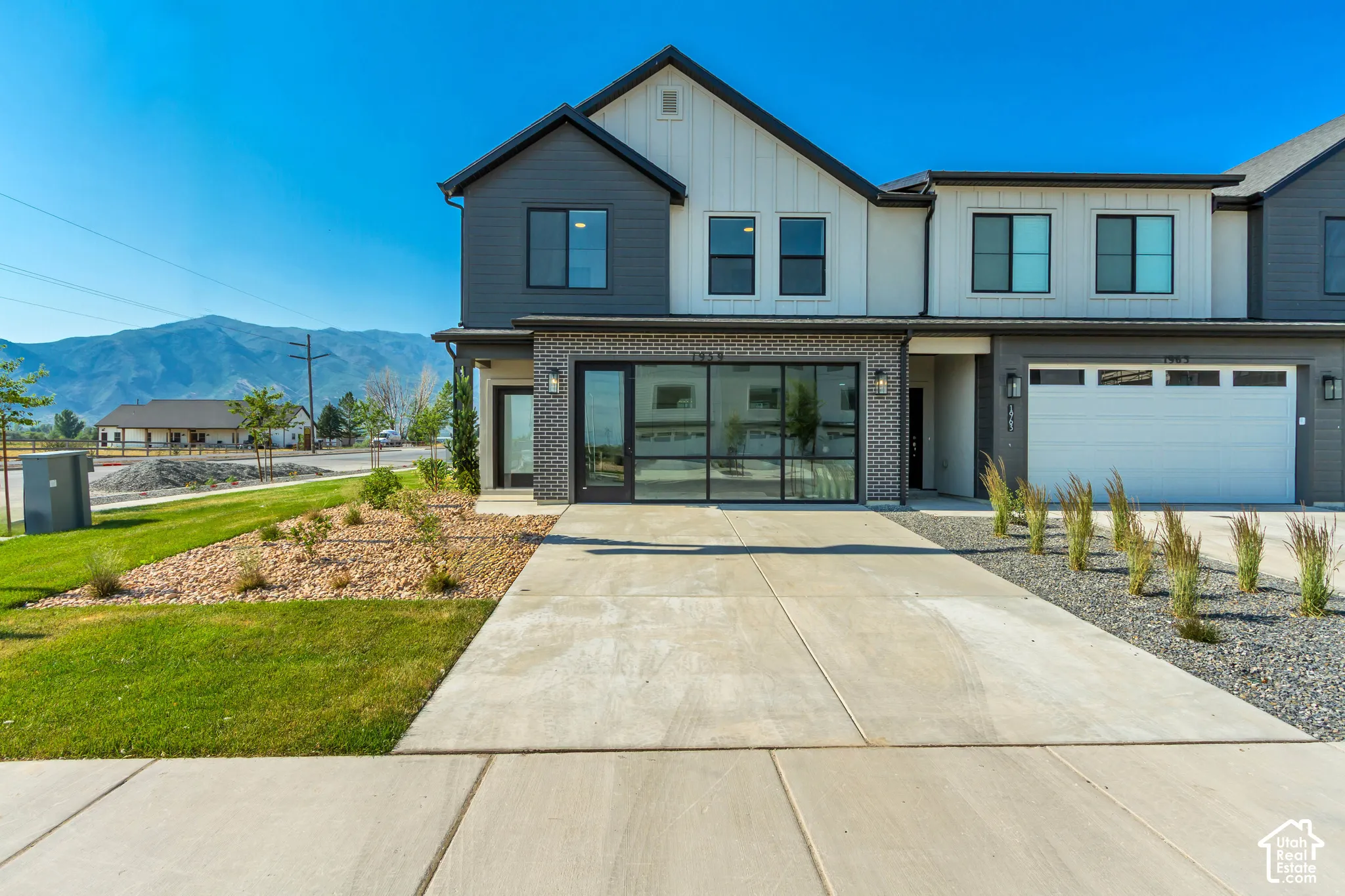 Contemporary exterior with dark siding accents, white vertical siding, and a brick facade