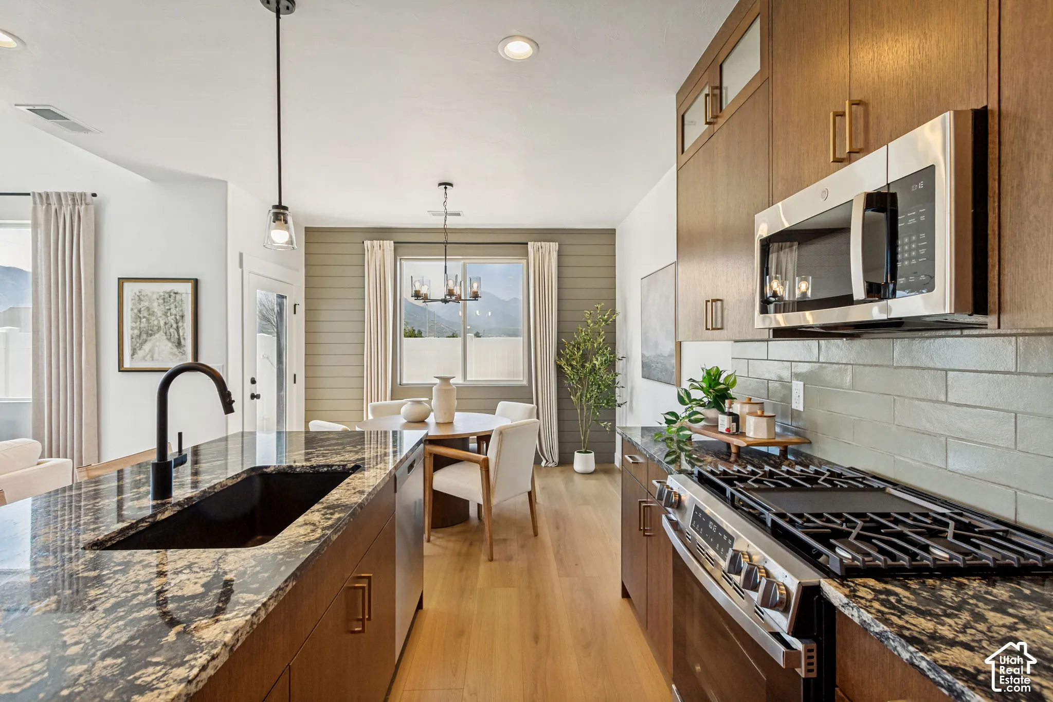 Kitchen featuring wood-finish cabinetry, granite countertops, stainless steel appliances, a tiled backsplash, and wood-finish flooring