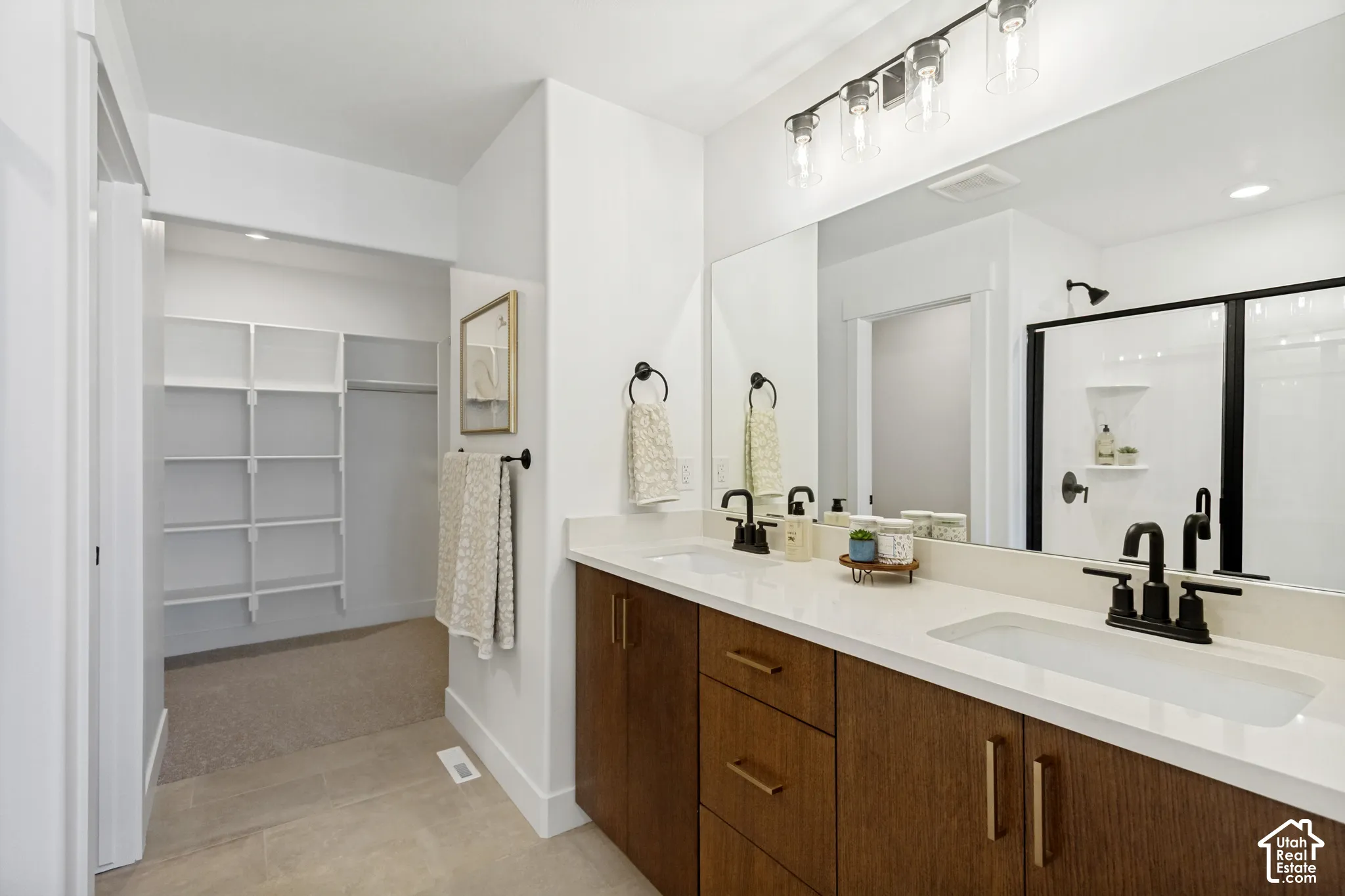 Dual vanity with quartz countertop, wood-finish cabinetry, and matte black fixtures