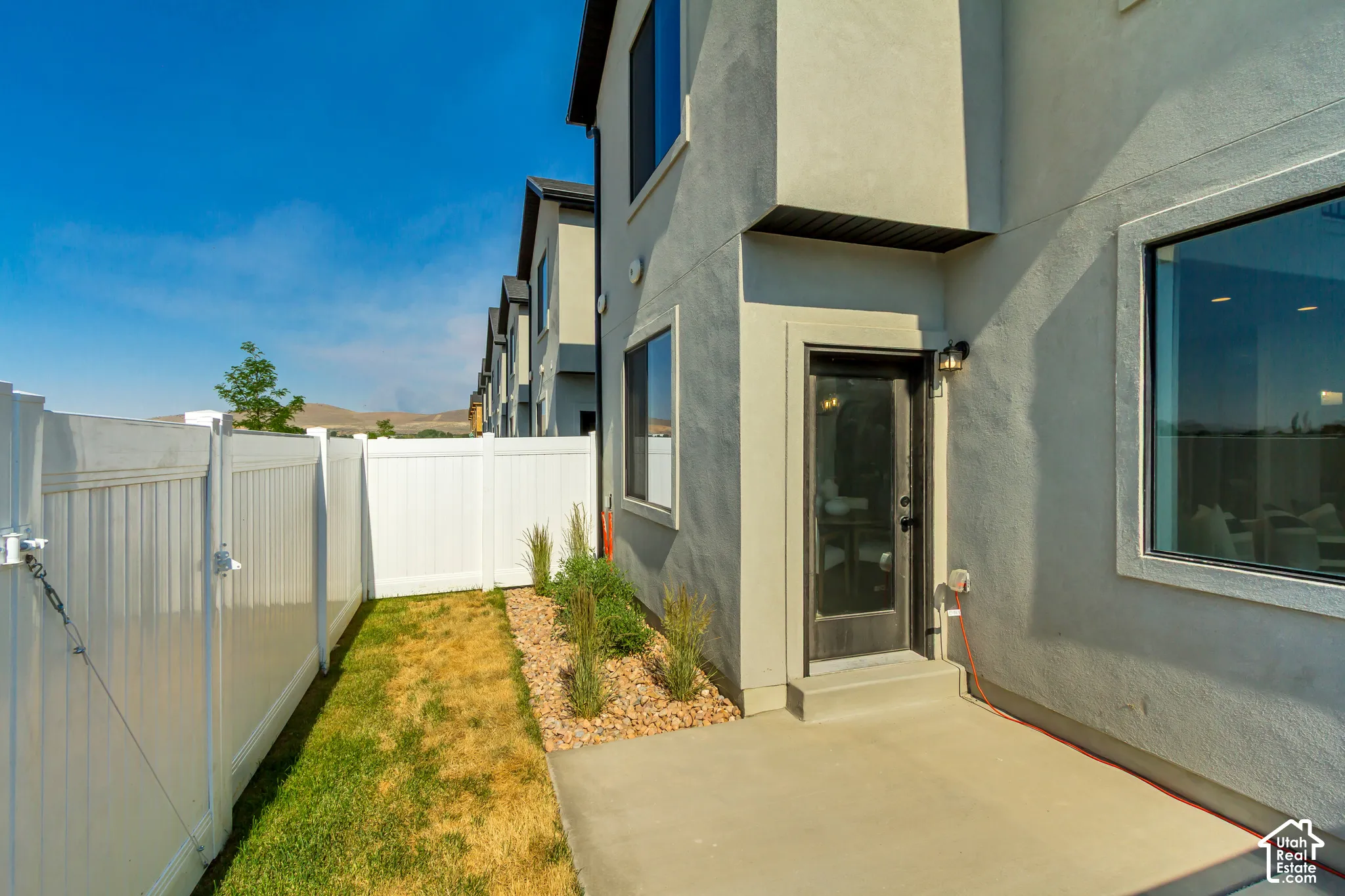 Private outdoor patio with a concrete surface, bordered by a white vinyl fence
