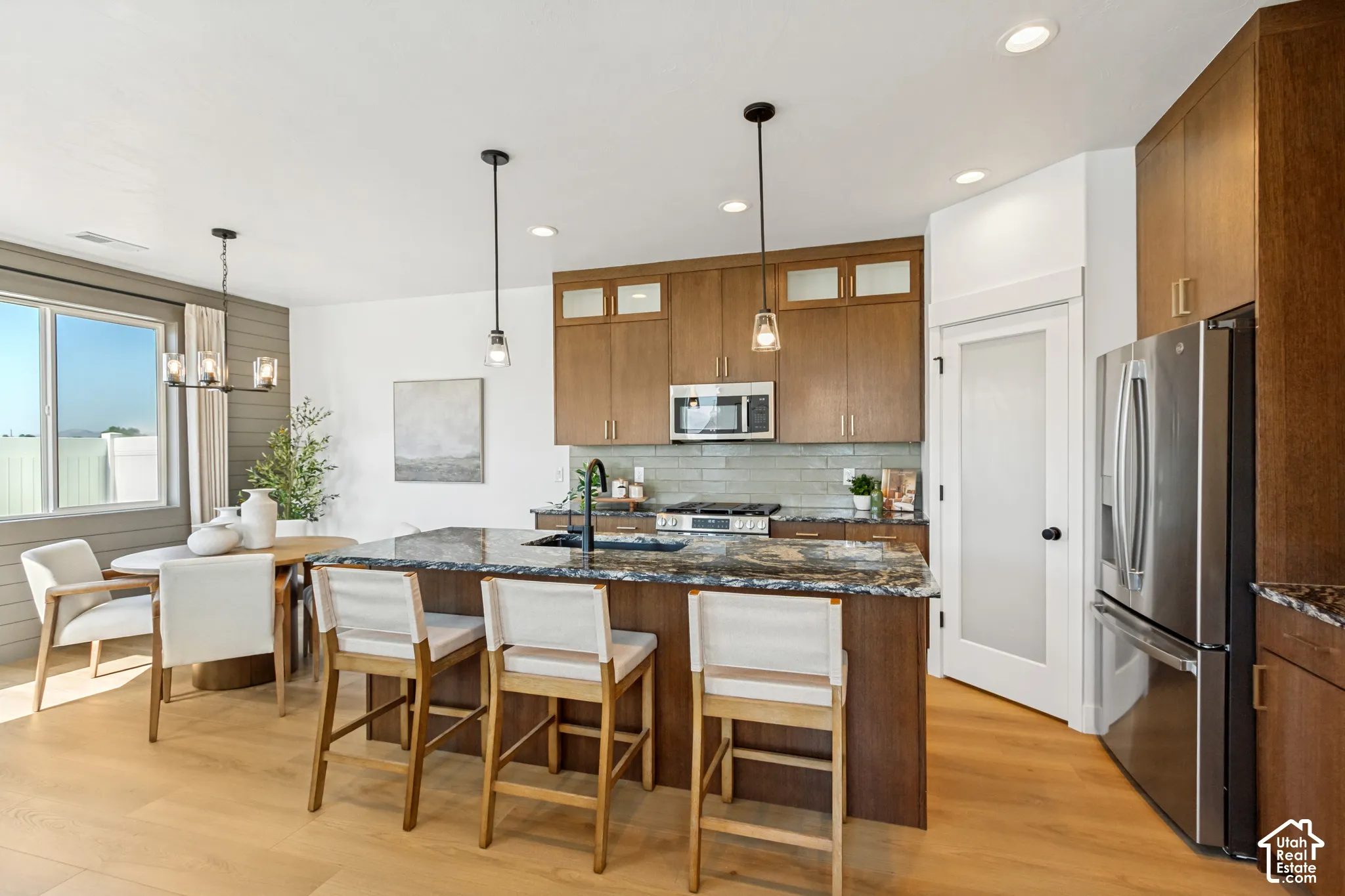 Kitchen with wood-finish flooring, an island featuring a dark speckled countertop, and wood cabinetry