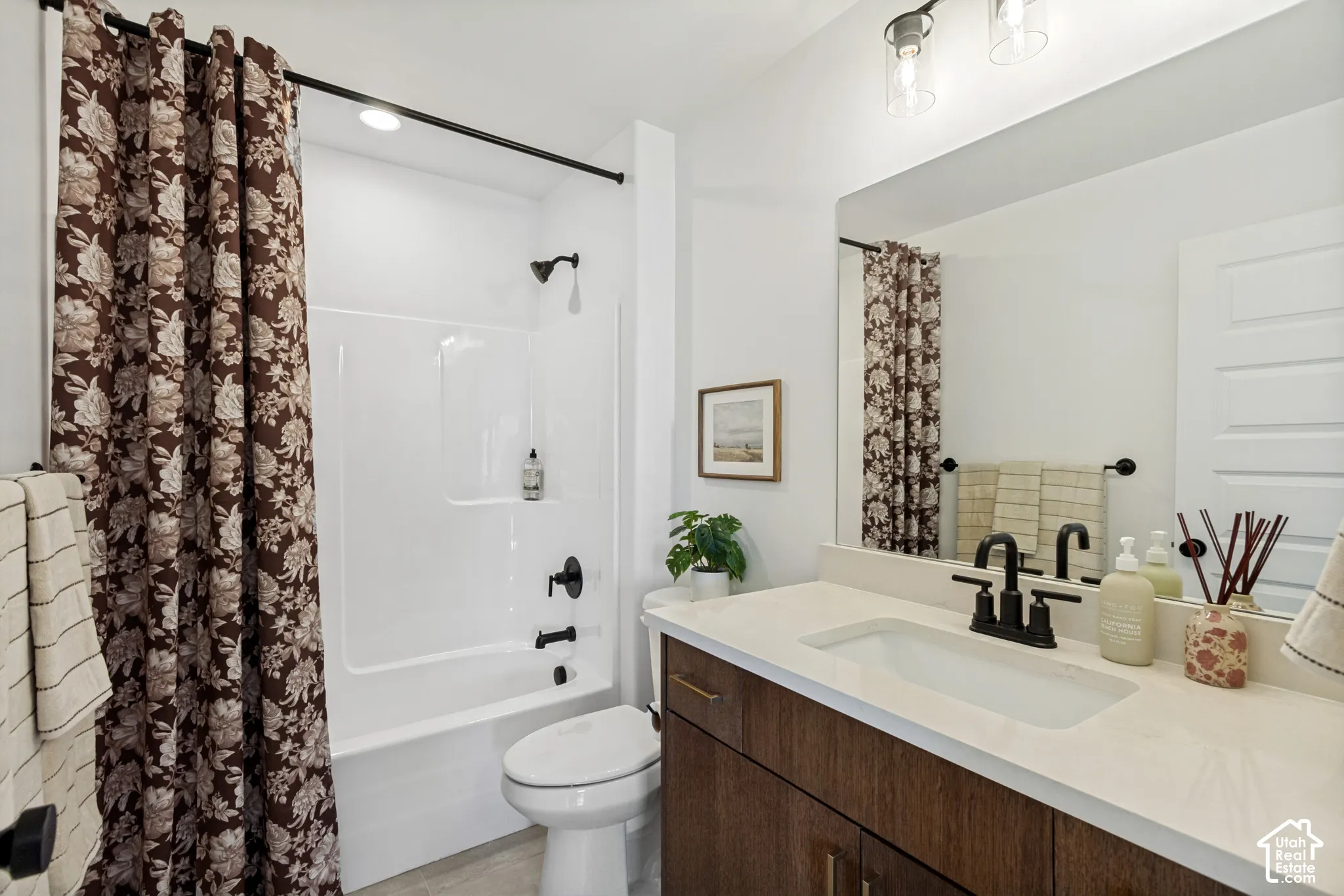 Built-in vanity with a single basin, light-toned countertop, wood-finish cabinetry, and matte black fixtures