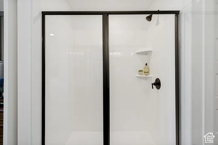 White shower enclosure with a dark-framed sliding glass door