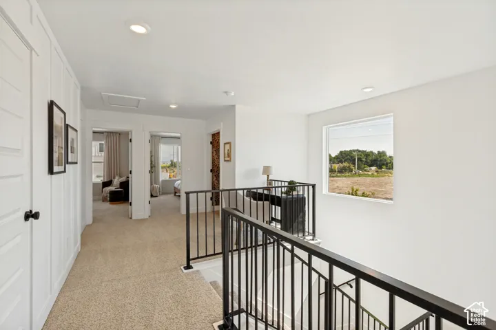 Upper-level hallway with neutral carpeting, recessed lighting, and white paneled walls