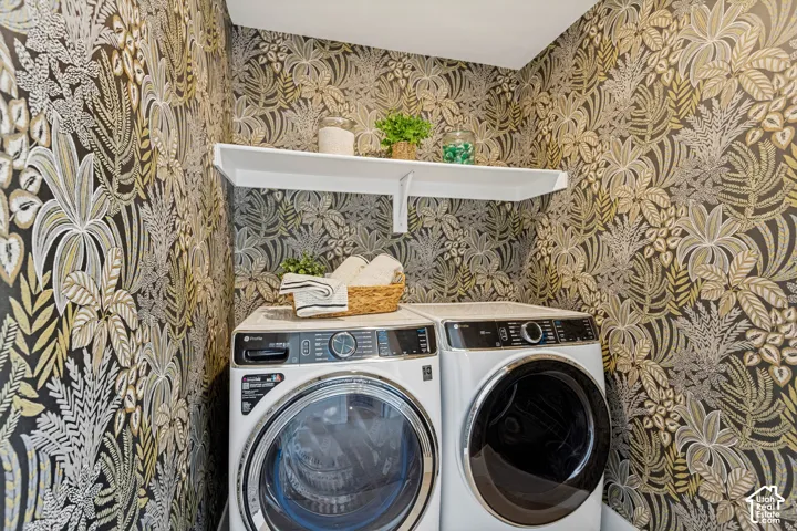 Laundry area featuring patterned wallpaper, white wall-mounted shelving, and appliances