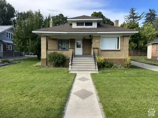 Brick exterior featuring a front porch with railing, a dormer, and a concrete walkway