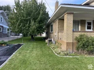 Brick exterior with a covered porch, mature tree, and established lawn