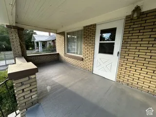 Covered porch with a brick facade and a decorative storm door