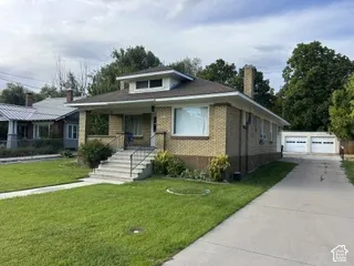 Brick exterior with a covered porch, concrete driveway, and a detached two-car garage