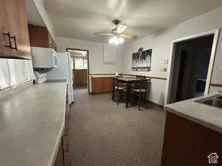 Kitchen featuring wood-finish cabinetry, light-toned countertops, and carpet flooring
