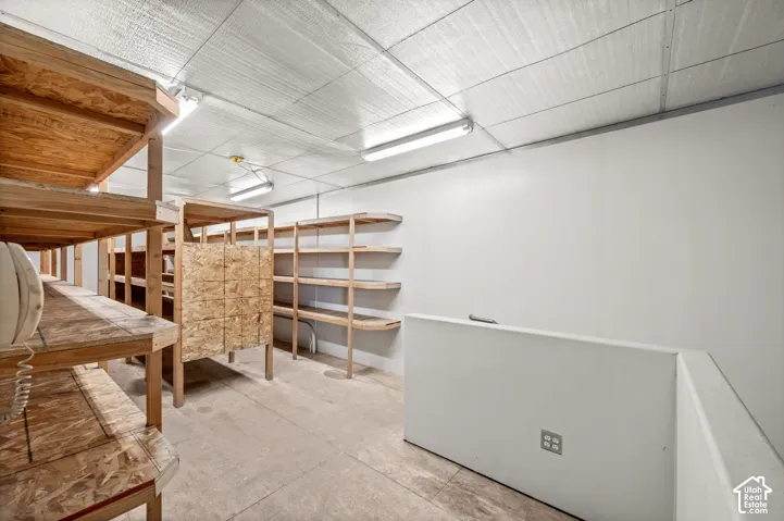 Expansive storage area featuring multiple wood shelving units, a finished concrete floor, and fluorescent overhead lighting