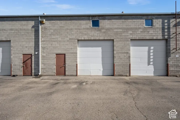 Concrete block exterior with multiple roll-up doors, individual entry doors, and upper-level windows