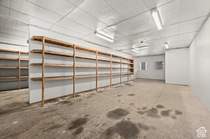Expansive storage area featuring multiple rows of built-in wooden shelving, concrete flooring, and fluorescent ceiling lighting