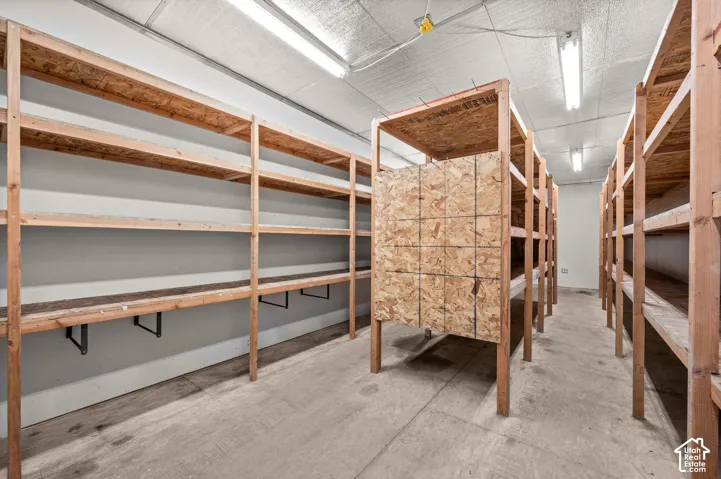 Concrete flooring, extensive wood shelving, multiple fluorescent light fixtures, and a textured ceiling