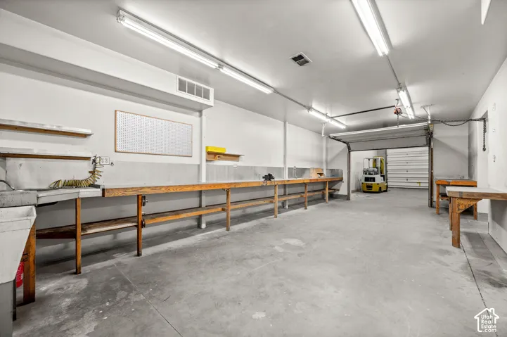 Concrete flooring with expansive workspace, integrated utility sink, and wall-mounted pegboard