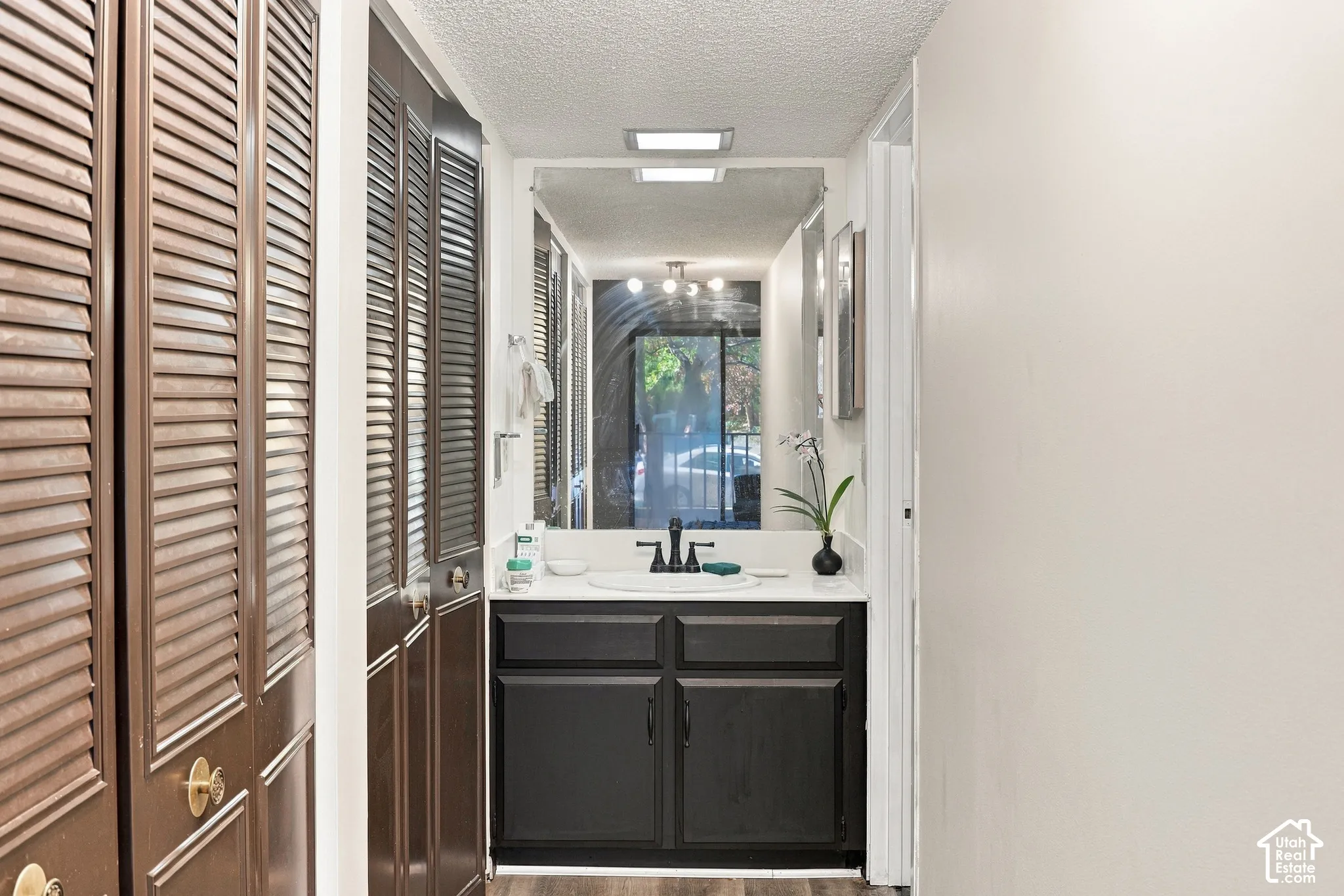 Vanity with a white countertop and rectangular undermount sink, complemented by a black faucet and dark wood-finish cabinetry