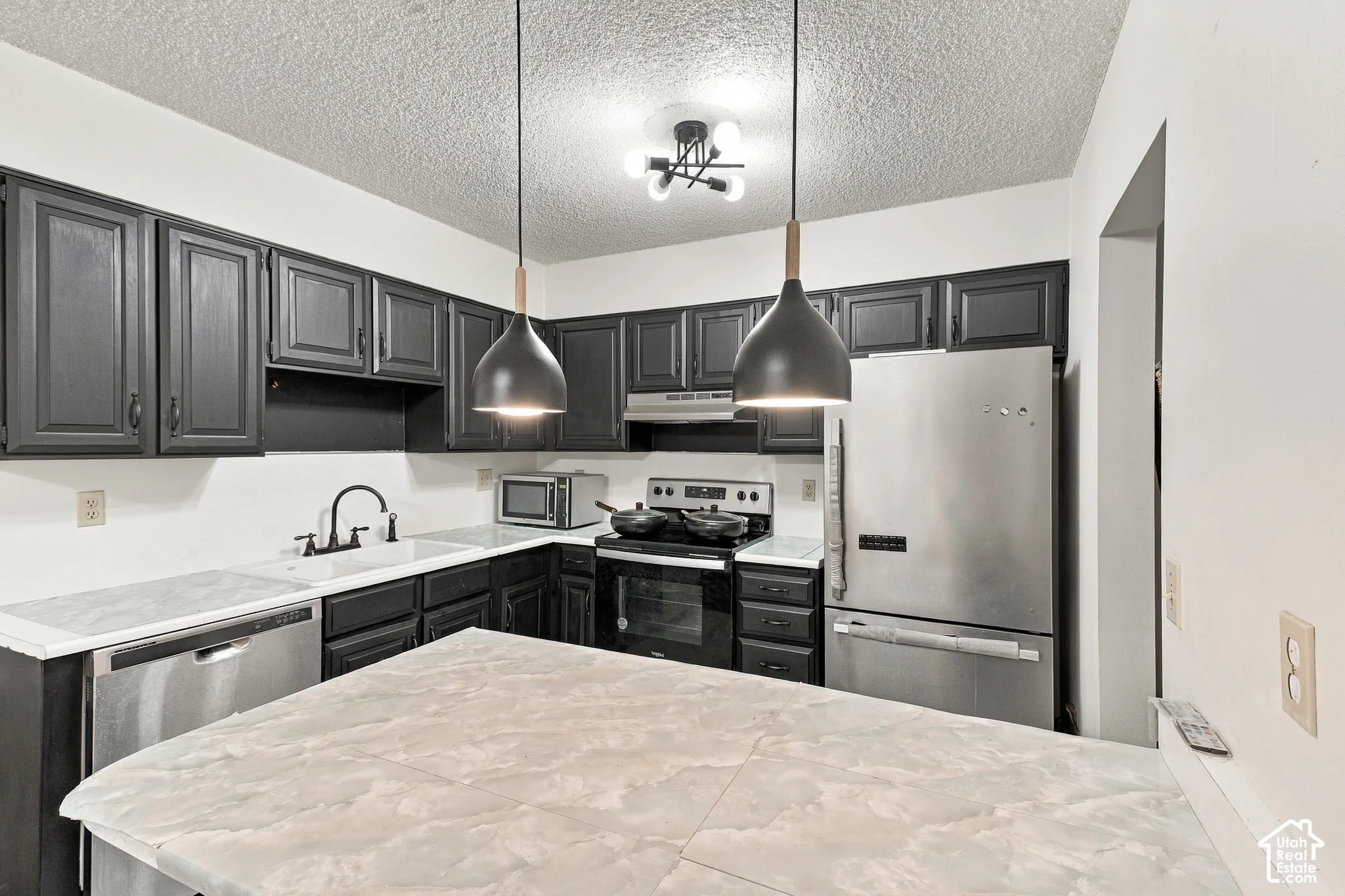 Kitchen featuring dark cabinetry, light-toned countertops, and stainless steel appliances