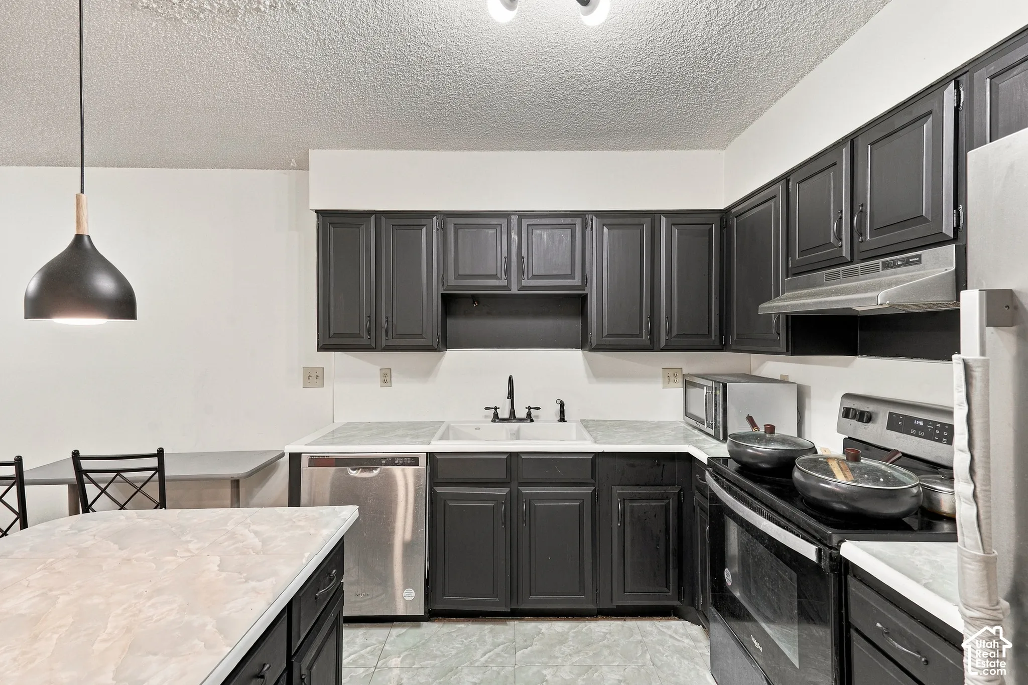 Kitchen featuring dark cabinetry, light countertops, and stainless steel appliances