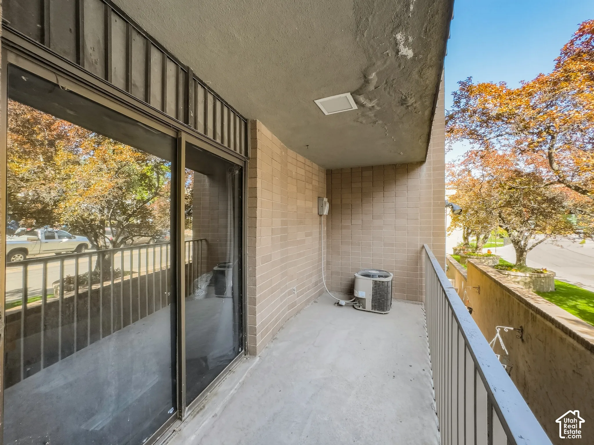 Balcony with concrete flooring, metal railing, and brick wall