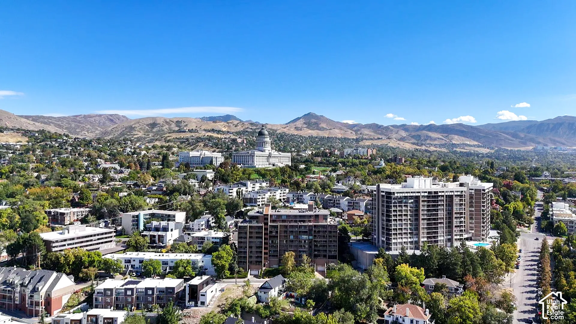 Mountain backdrop, urban setting, high-rise buildings, residential structures, tree-lined streets