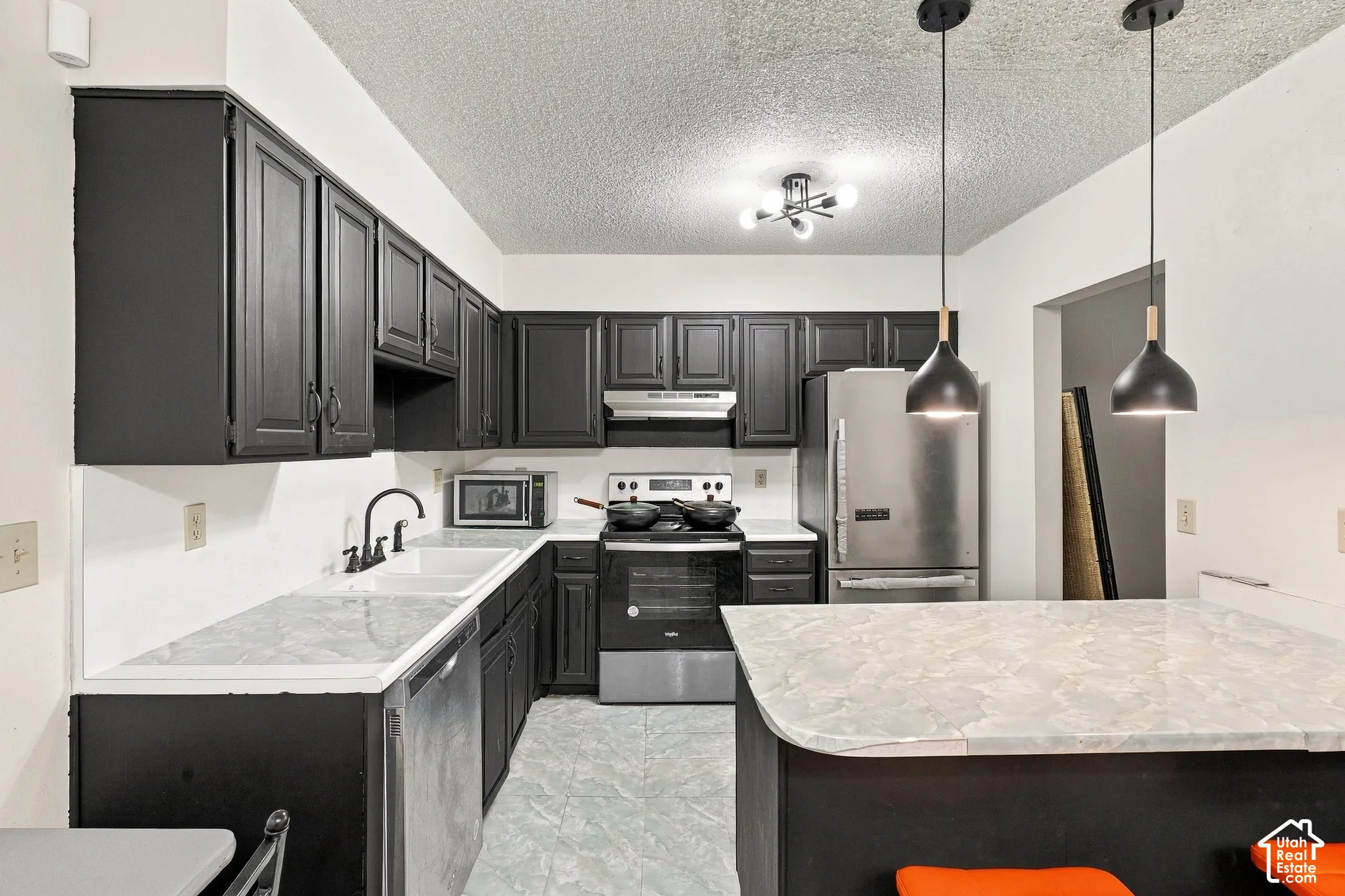 Kitchen featuring black cabinetry, light-toned countertops, and stainless steel appliances