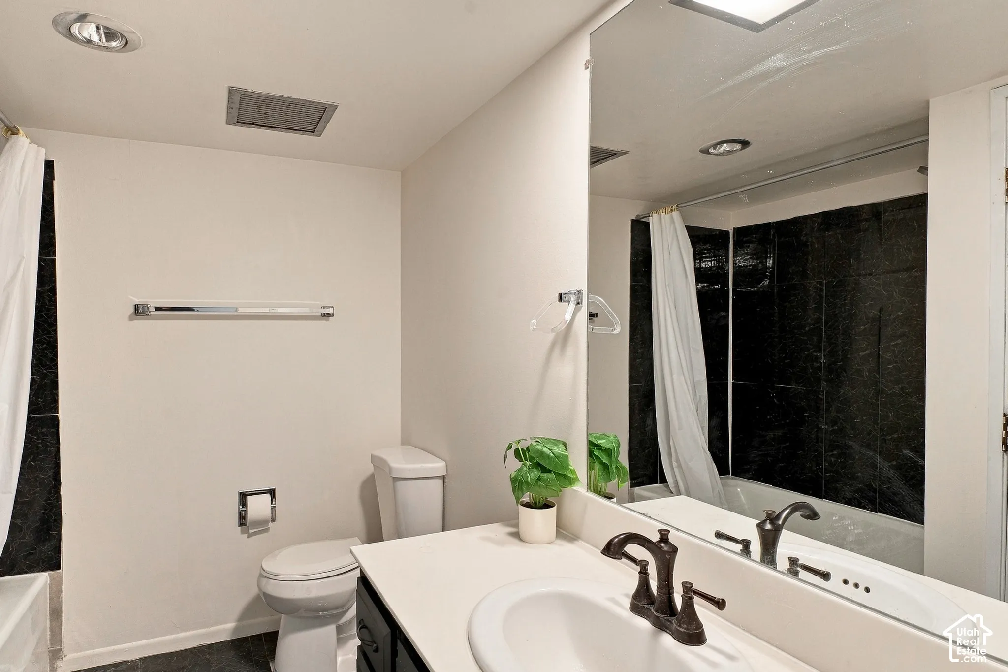 Bathroom featuring a white vanity with an integrated sink, dark bronze-finish faucet, and a large wall-mounted mirror