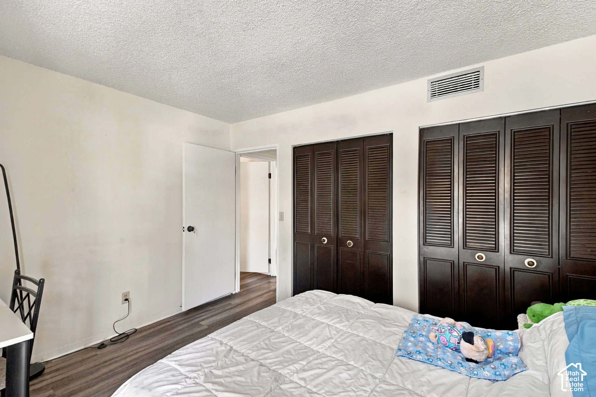 Wood-finish flooring with white walls and a textured ceiling