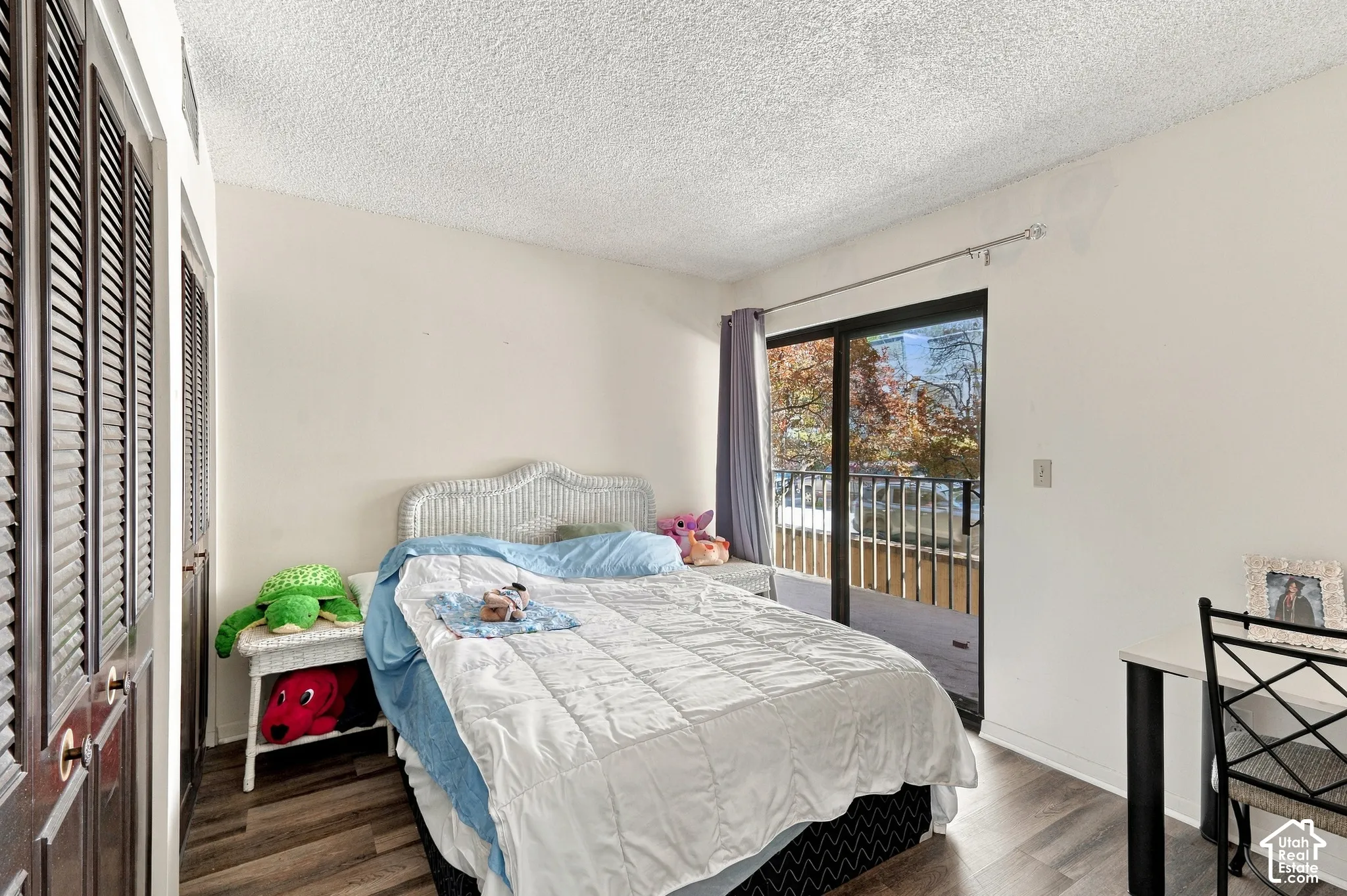 Dark wood-finish louvered closet doors, wood-finish flooring, sliding glass door, and exterior balcony
