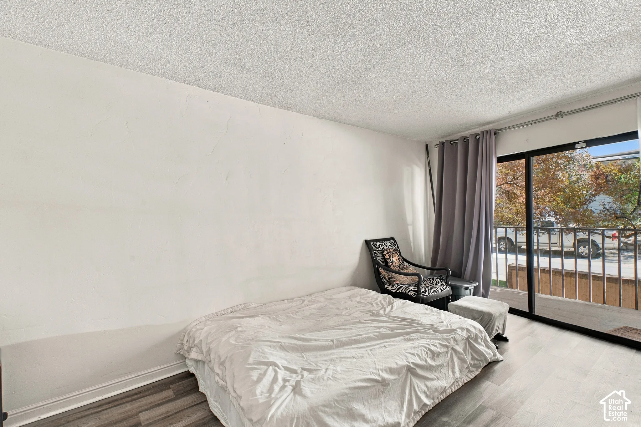 Wood-finish flooring, white wall finishes, and a sliding glass door providing balcony access