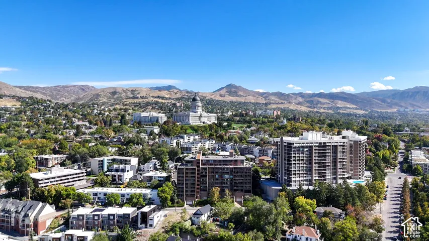 Mountain backdrop, urban setting, high-rise buildings, residential structures, tree-lined streets