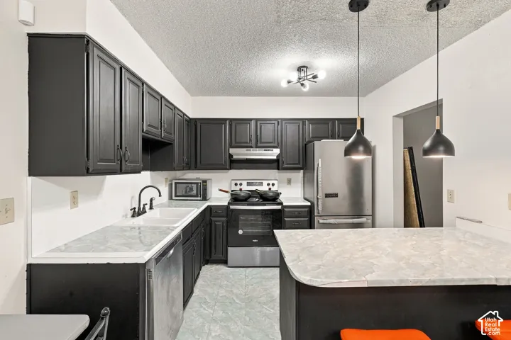 Kitchen featuring black cabinetry, light-toned countertops, and stainless steel appliances