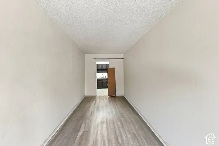 Wood-finish flooring with neutral wall paint and a textured ceiling
