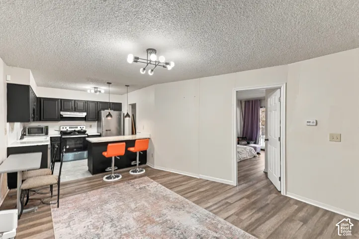 Kitchen featuring dark cabinetry, stainless steel appliances, and a breakfast bar