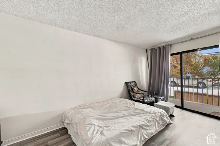 Wood-finish flooring, white wall finishes, and a sliding glass door providing balcony access