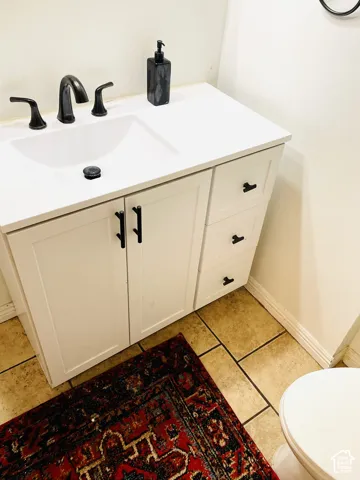 White vanity with shaker-style cabinet doors, integrated sink, and dark bronze hardware