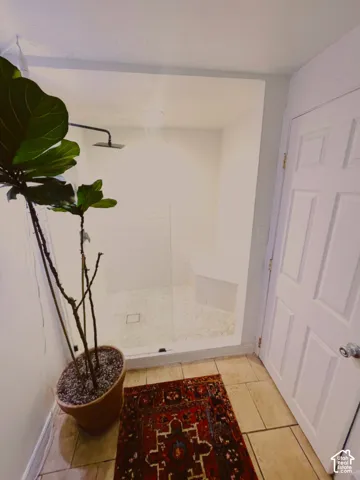 Tiled flooring leading to a glass-enclosed shower with pebble-finish base and built-in bench