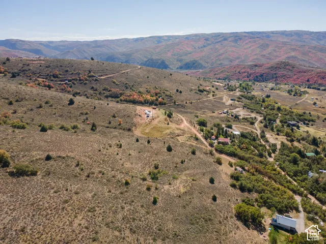 Expansive terrain featuring natural vegetation, distant mountain range, and scattered structures