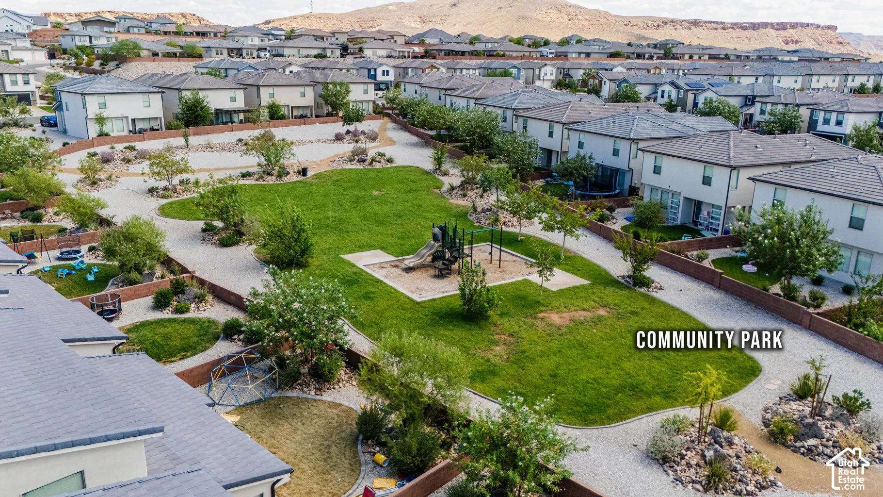Central community park featuring a grass lawn, playground structure, and landscaped pathways