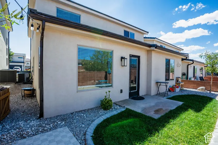 Stucco exterior with multiple windows, a rear entry door, and an outdoor patio area