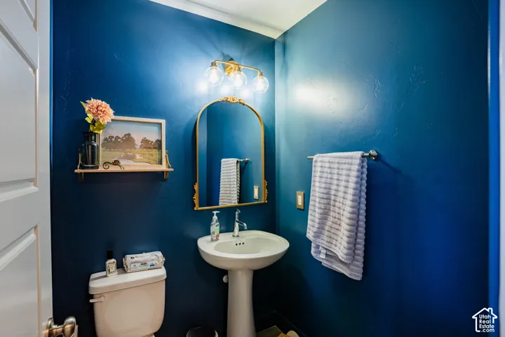 Pedestal sink with chrome faucet, framed mirror, and a three-light vanity fixture